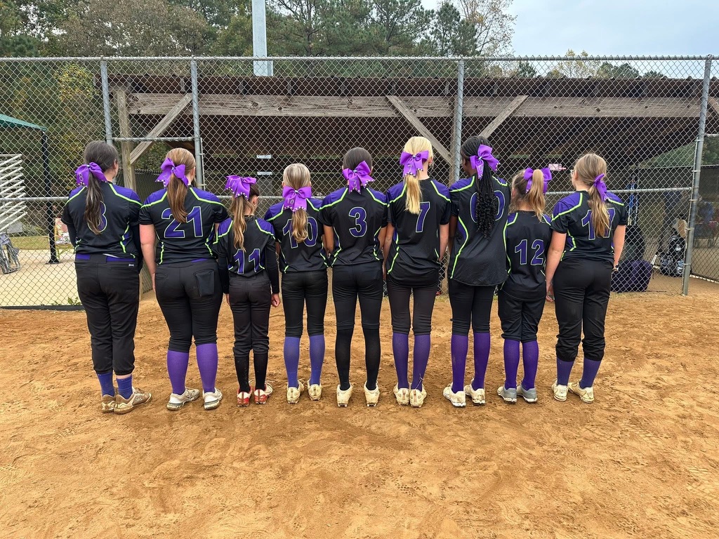 A real girls softball team posing together on the field